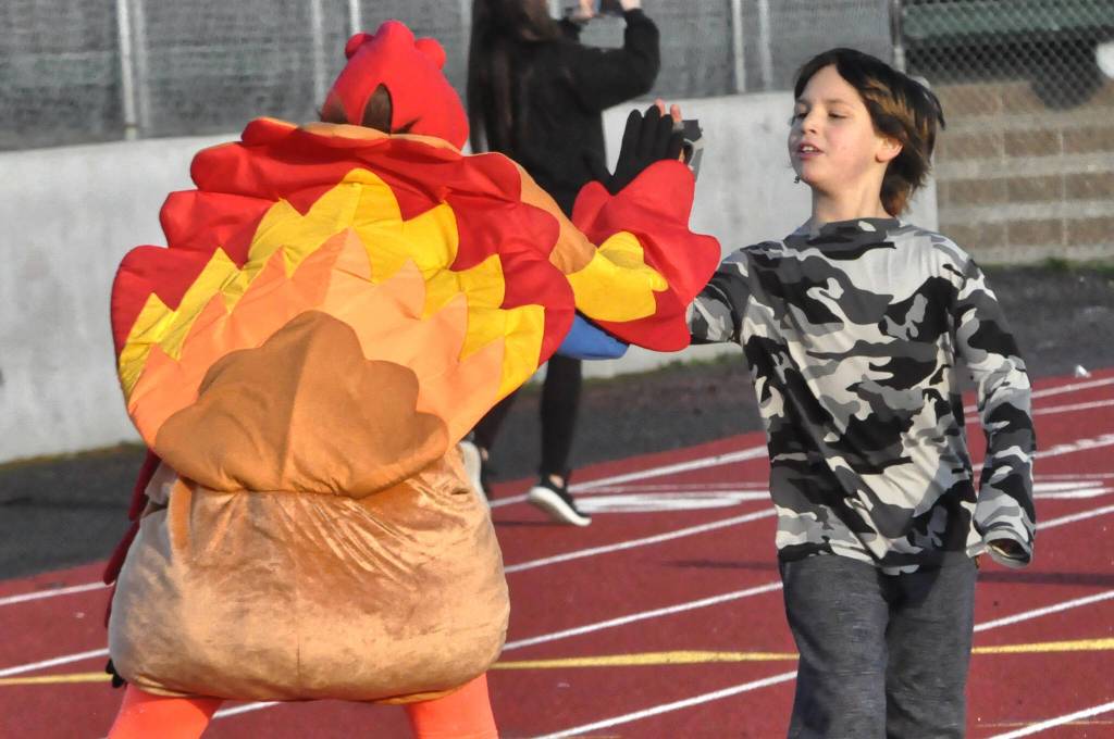 Sequim Gazette photo by Matthew Nash/ Atticus Ball high fives Helen Haller Elementary principal Becky Stanton during the Turkey Trot.