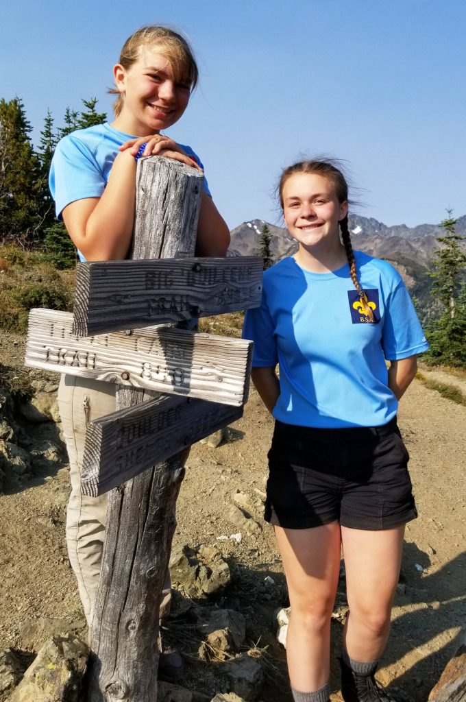 Photo courtesy Peter Craig/ Grace Kathol and Jenna Mason stand a sign post for Marmot Pass during a scouting adventure.