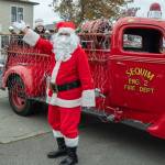 Sequim Gazette photo by Emily Matthiessen/ Young Daisy Molles peeks at Santa Claus after he disembarks from his firetruck.