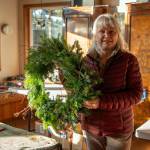 Emily Matthiessen/ Ann Johnson of Lazy J Tree Farm and two other women make Christmas wreaths in a sunlit room of the Johnson home.