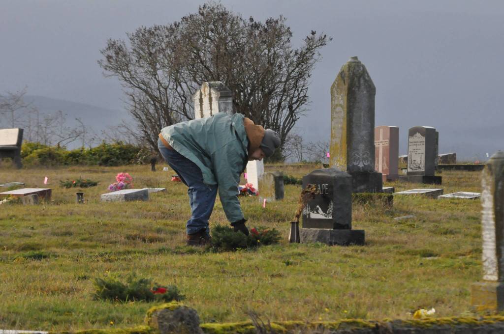 Sequim Gazette photo by Matthew Nash/ Ken Cox, ret. U.S. Army Cpl., places a wreath on veterans grave in Dungeness Cemetery on Dec. 14 for National Wreaths Across America Day.