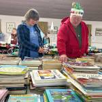 Volunteers Joy Edge and Steve Downer look through the books at Toys for Sequim Kids on Dec. 17. Edge said she learned about the event in the newspaper a few years ago and was able to help this year for the first time.