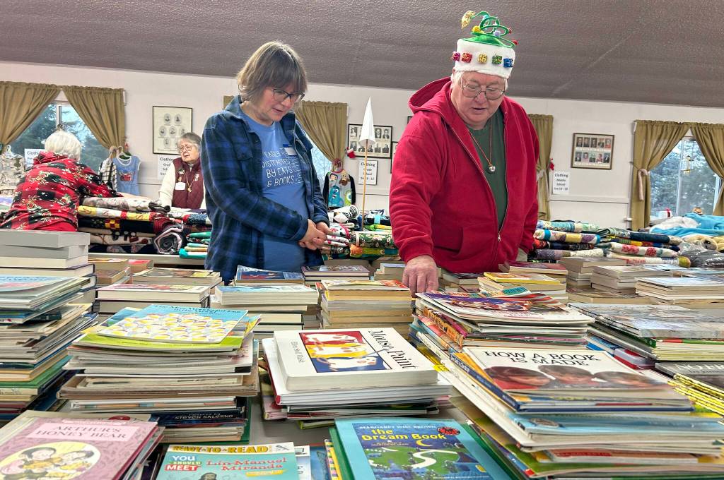 Volunteers Joy Edge and Steve Downer look through the books at Toys for Sequim Kids on Dec. 17. Edge said she learned about the event in the newspaper a few years ago and was able to help this year for the first time.