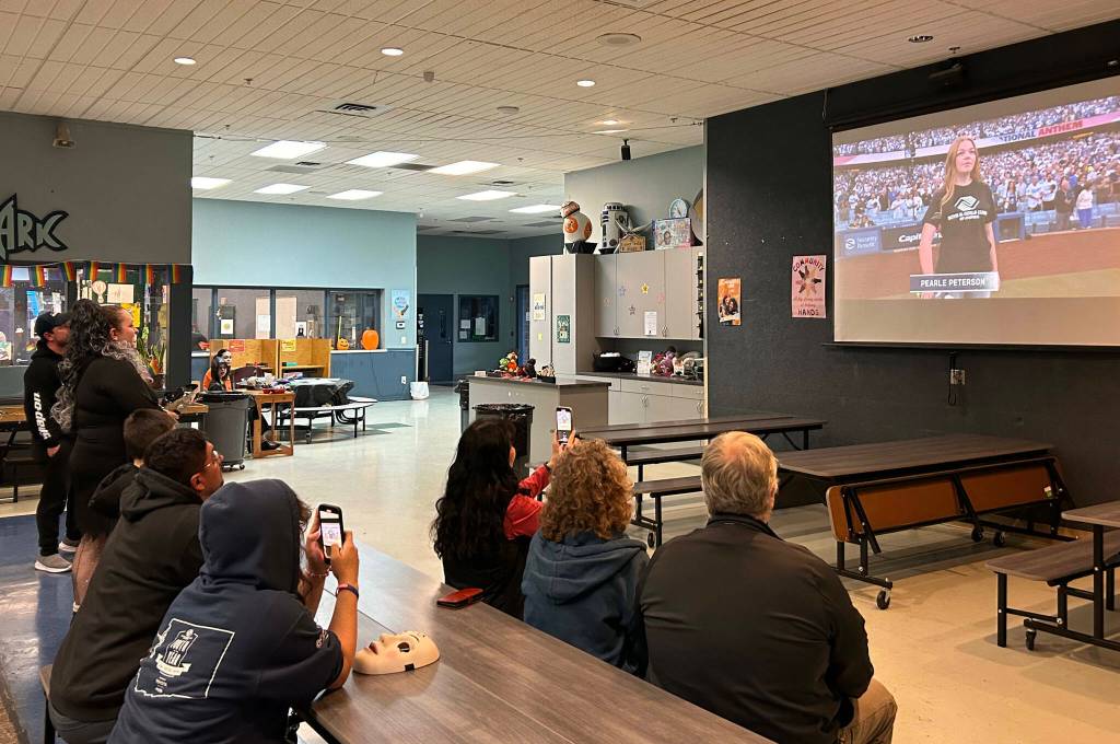 Sequim Gazette photo by Matthew Nash Mary Budke, executive director of the Boys Girls Clubs of the Olympic Peninsula, and fellow supporters cheer for Pearle Peterson on Oct. 26 from inside the Sequim club as Peterson sings the national anthem at game two of the World Series.