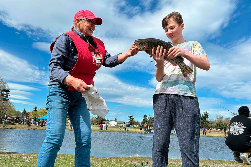 Sequim Gazette photo by Matthew Nash
Austin Neuharth, 12, of Sequim catches a fish at his first visit to Kids Fishing Day on April 20 as volunteer Pat Lundin with the North Olympic Peninsula Chapter of Puget Sound Anglers helps him ready the fish for cleaning.