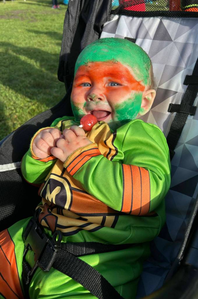 Sequim Gazette photos by Matthew Nash
As Michelangelo the Teenage Mutant Ninja Turtle, baby Ivar enjoys a lollipop with his parents Jessica and Dustin Baker at the Sequim Prairie Granges Fall Festival and Trunk-or-Treat on Oct. 26.