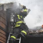 Sequim Gazette file photo by Matthew Nash/ Firefighter/EMT Tyler Campbell with Clallam County Fire District 3 vents a roof during a house fire last Nov. 12 near Sequim.