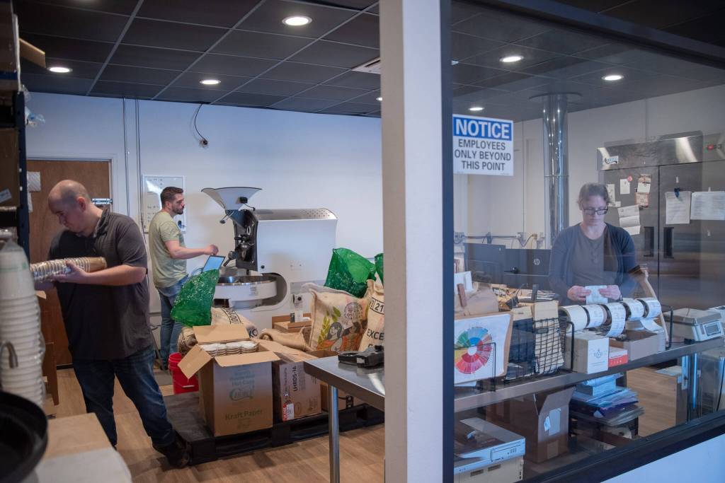 Sequim Gazette photo by Emily Matthiessen
Barista Zane Haden, left, and owners Rod and Megan Dirks attend to roasting day tasks Saturday at Sequims Essence Coffee Roasters.
