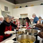 Sequim Gazette photos by Kathy Cruz
At noon every Wednesday, the kitchen at St. Lukes Episcopal Church in Sequim is a flurry of activity as volunteers begin serving a free lunch that consists of hot soup, salad, a bread item (yeast rolls, biscuits or corn muffins and a dessert. Here, the cooking team of Janet Popelka and Ray Kaminsky ladle soup into bowls as other volunteers bustle around them.