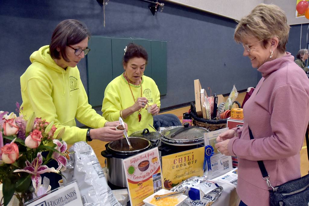 Photo by Keith Thorpe, Olympic Peninsula News Group/ Jen Colmore, left, and June Nicholas of the Sequim Food Bank serve a sample of chili to judge Monica Dixon of Sequim during the Community Chili Cookoff on Feb. 17 at the Sequim Boys & Girls Club. They won $500 for the organization with Nicholas chili.