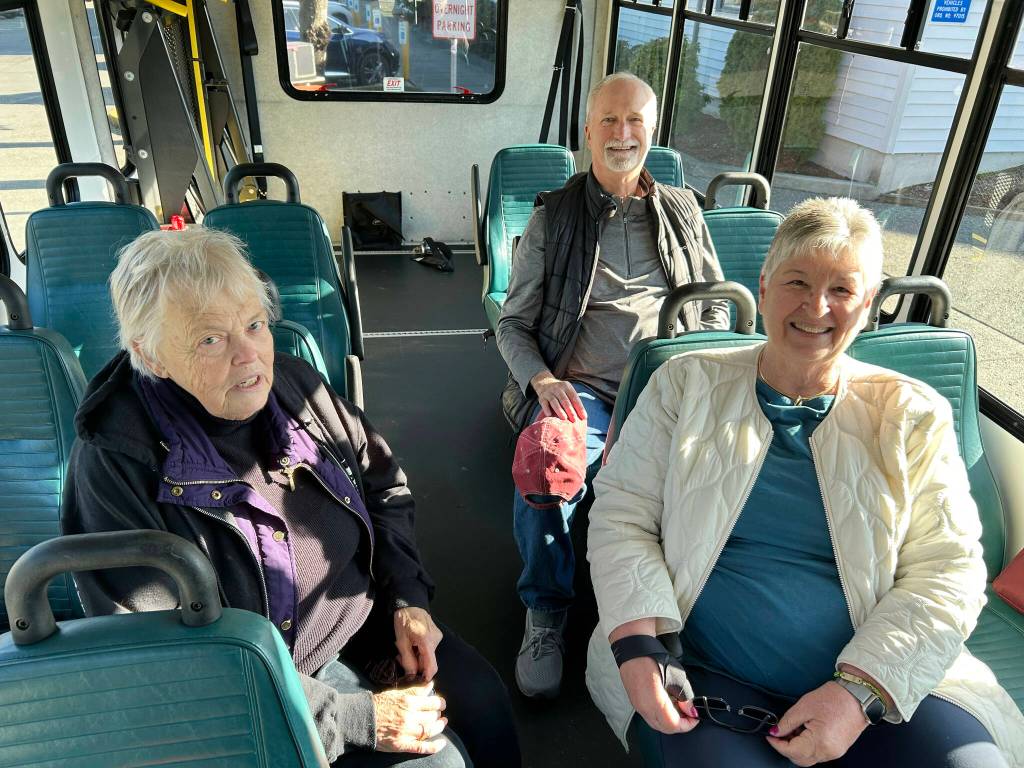 Sequim Gazette photo by Matthew Nash/ Maryln Lovell of Sequim and Barb and Mike Speer of Bonney Lake sit inside a new shuttle bus that the estate of their friend/sister Sherry Nagel paid for at the YMCA of Sequim to help transport seniors and children.