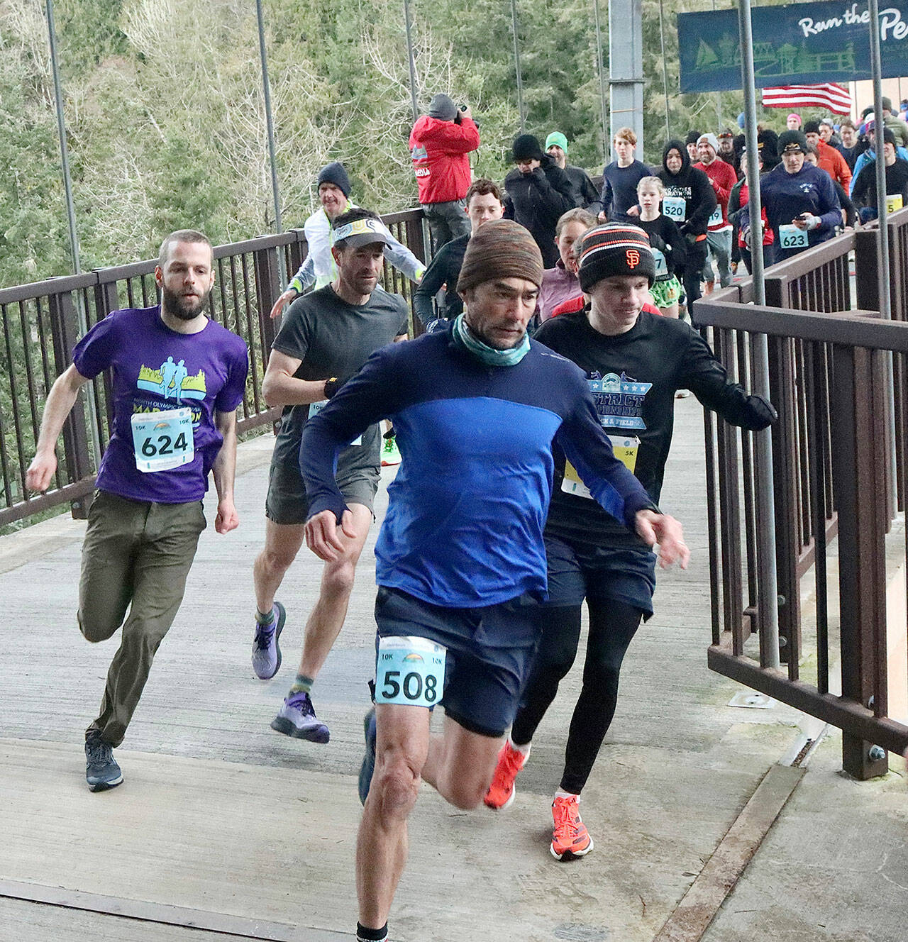 Dave Logan/for Olympic Peninsula News Group/ Runners take off at the Elwha River Pedestrian Bridge on Saturday morning in the Elwha Bridge Run 5K/10K, the first race in the Run the Peninsula series. In this photo are the 5K winner, Kyle Bardwell in the San Francisco Giants cap, 10K winner John Mauro of Port Townsend in the visor and 10K womens winner, Eleanor Jones, 12, of Sequim (black top, no hat and green shorts).
