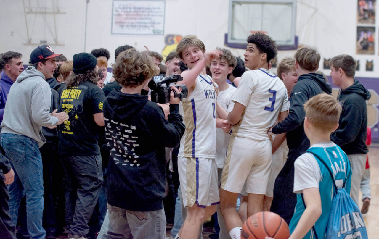 Sequim Gazette photo by Emily Matthiessen/Sequim students storm the court and celebreate with Ethan Melnick (0) and Solomon Sheppard (3) after the Wolves beat Bremerton 66-61 on Monday night to earn a share of the Olympic League boys basketball championship. Sequim and Bremerton will play in Poulsbo Wednesday in a rubber match to determine playoff seeding.