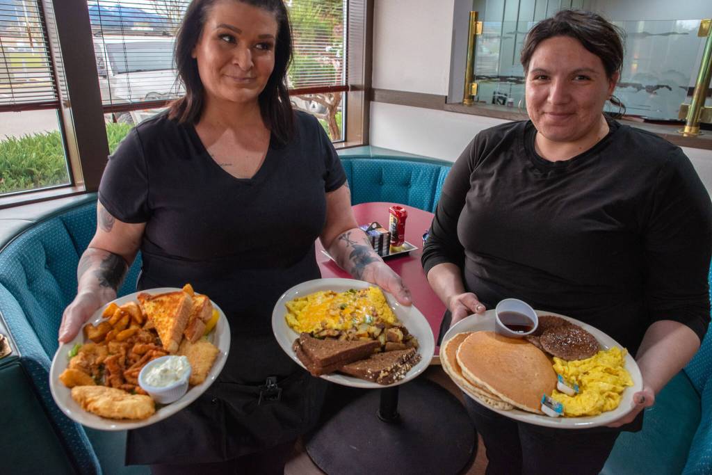 Sequim Gazette photo by Emily Matthiessen/ Waitresses Michelle Brianne Steward and Trisha Stigall hold platters food offered on the menu at the newly opened Paradise Cafe: Captains Platter, Denver Omelette and 2-2-2.