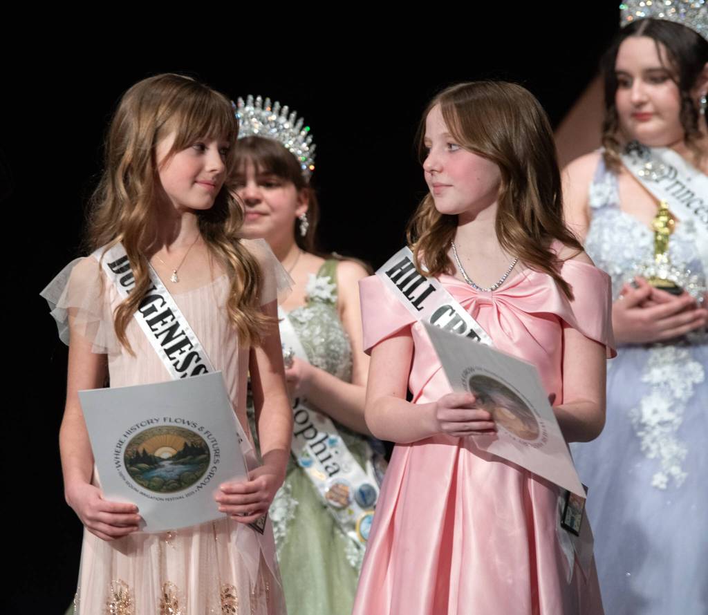 Sequim Gazette photo by Emily Matthiessen/ Madelyn Davis and Savannah Fuller exchange glances as they wait to read essays about their experience of Sequim and then be crowned junior princesses during the Irrigation Festival Royalty Pageant on Feb. 22.