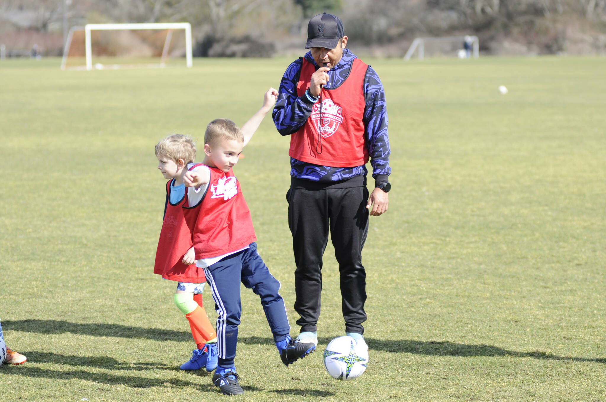 Juan Carlos Cisneros-Lopez, Sequim Junior Soccers new director of coaching, works with players, such as Barrett Gerdes, 6-and-a-half, at a preseason skills camp on March 1 at the Albert Haller Playfields. In the coming months, Cisneros-Lopez said he plans to develop a curriculum for players and coaches to succeed.