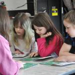 Sequim Gazette photo by Matthew Nash/ Second graders, from left, Envi Chaffin, Stella Mueller and Taelynn Savell reads about inventions with eighth grader Frances Haskins during Read Across America Day in Sequim.