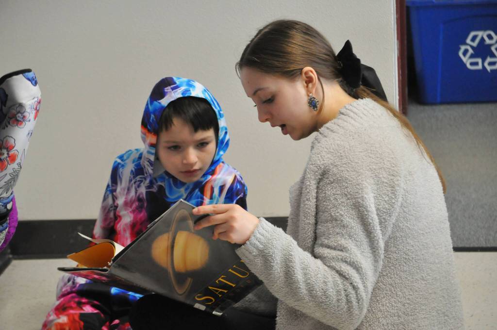 Sequim Gazette photo by Matthew Nash/ Caroline Candle, a Sequim eighth grader, reads about Saturn with second grader Caden Reyes during Read Across America Day.