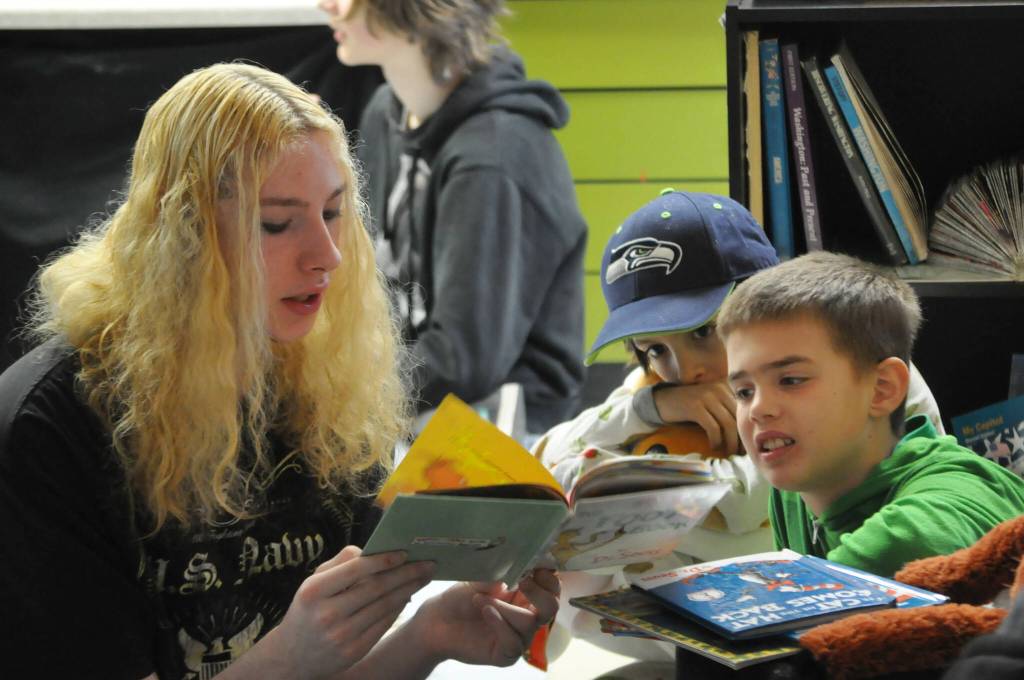 Bottom Left: Sophomore Stanley Baker reads Dr. Seuss books with third graders Jethro Welch and Beckett Thomas during Sequims Read Across America Day.