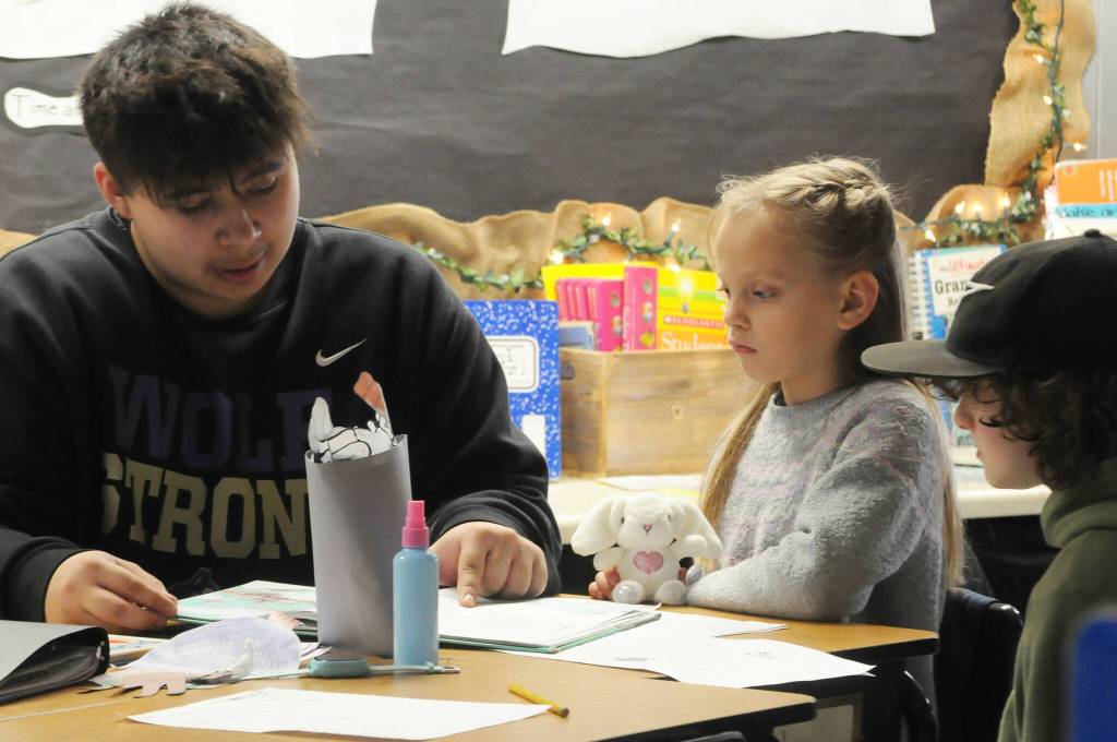 Sequim Gazette photo by Matthew Nash/ Sequim high schooler Kingston Stevens reads to third graders Marlee Murphy and Lincoln Barrett during Sequims Read Across America Day event.