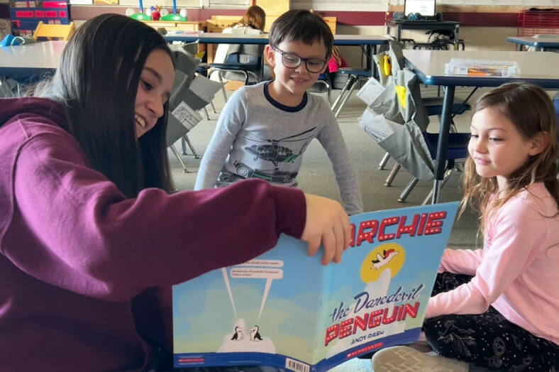 Eighth grader Annalise Castelletti reads Archie the Daredevil Penguin to kindergarteners Jesse Maas and Ivory Lyckman at Greywolf Elementary for Sequims Read Across America event on March 7.