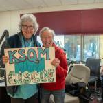 Sequim Gazette photo by Emily Matthiessen
 On March 1, Ciscoe Morris visits the KSQM headquarters and is presented with a welcoming poster by Tama Bankston, administrative director, while his broadcasting partner, Sassy Susan Sorensen looks on.