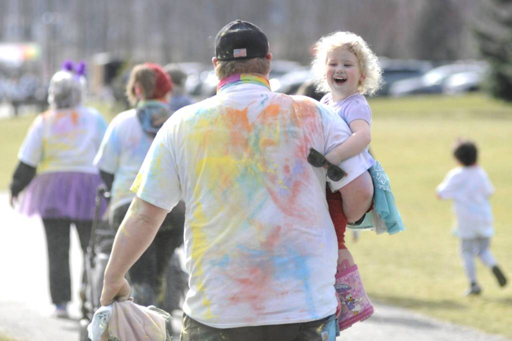 Sequim Gazette photo by Matthew Nash/ Chaz Bagley of Joyce carries his two-year-old daughter Magie through a color station much to her delight on March 8. Bagley said it was their first year and his wife and son ran the 5K.