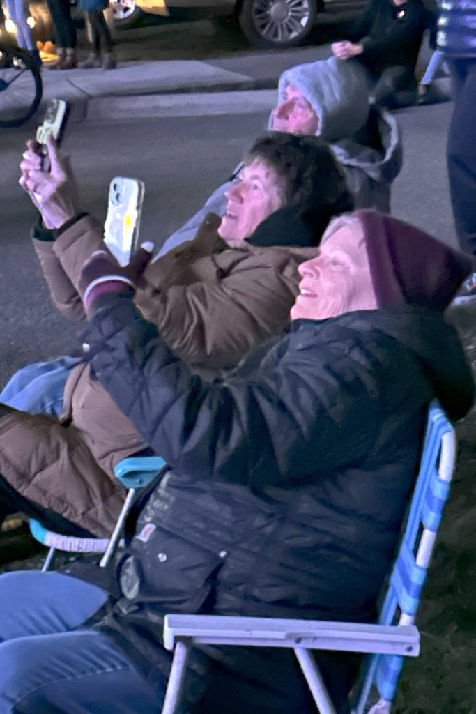 Sequim Gazette photo by Matthew Nash/ Terri Sagmoen, left, and Deedee Stevens, both of Sequim, capture a portion of the Illuminated Drone Show on their phones. The friends said theyve come to each show and that its gotten better every year.