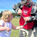 At left, Riley Lemon holds her fish while Chris Coventon with the North Olympic Peninsula Chapter of Puget Sound Anglers takes the hook out. She caught the fish during a field trip to the City of Sequims Water Reuse Demonstration pond in Carrie Blake Community Park.