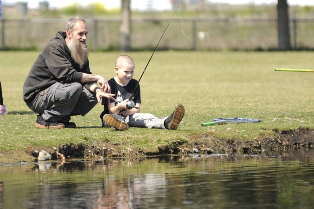 At right, Dusty Loftus Jr., 8, fishes with his dad Dusty Loftus, Sr. on 
April 18 in the Water Reuse Demonstration pond during a field trip for Sequim School District students.