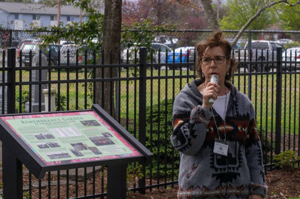 Sequim Gazette photo by Emily Matthiessen/ Susan Mannisto with the Sequim Prairie Garden Club speaks on April 19 at the dedication of Pioneer Memorial Parks Memorial Garden. Beside her a newly made informational sign details the history of the Garden.