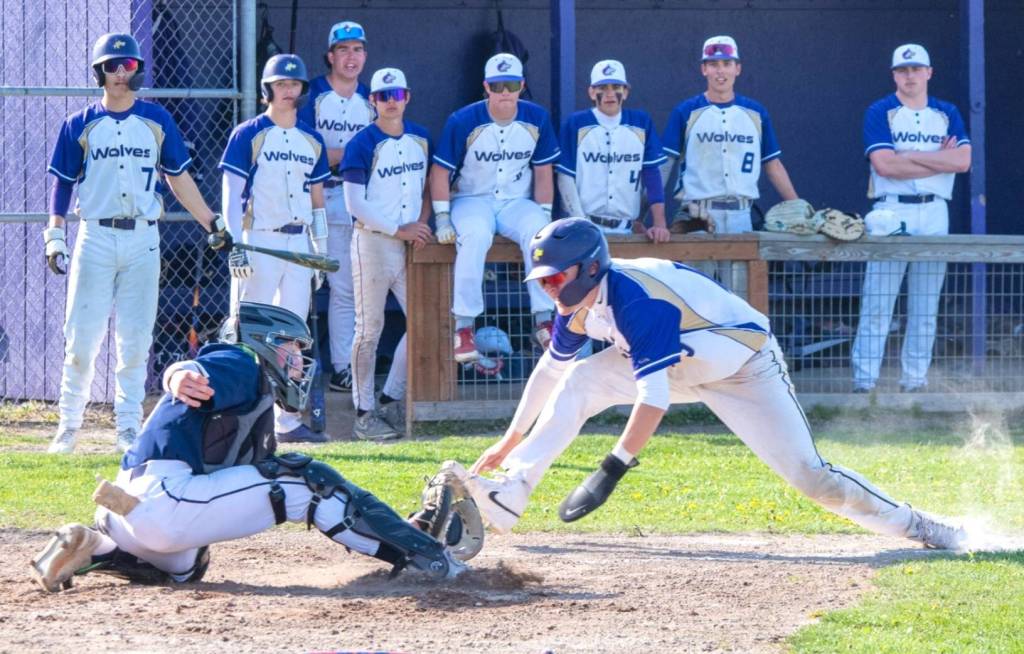 Sequim Gazette photo by Emily Matthiessen/ Devyn Dearinger stretches into home plate as teammates watch from the dugout during a close game that resulted in a 5-4 loss for the Wolves on April 24 at home against Cedar Park Christian.