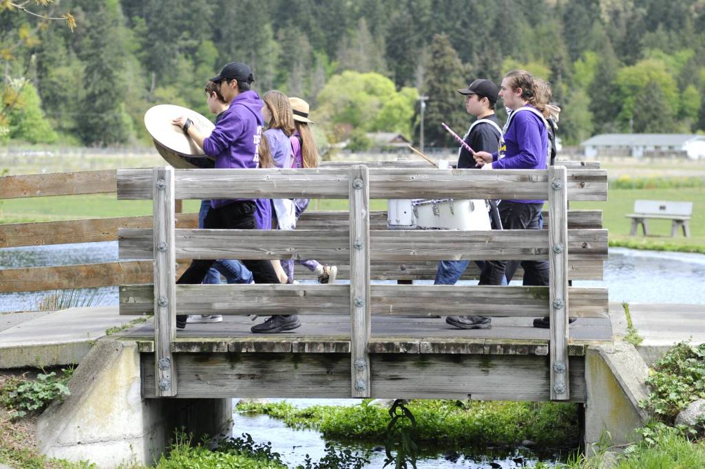 Sequim Gazette photo by Matthew Nash/ The Sequim Middle and High School Thunder Drumline makes its way across the bridge in the Water Reuse Demonstration pond in Carrie Blake Community Park during the Kids Parade on May 3.