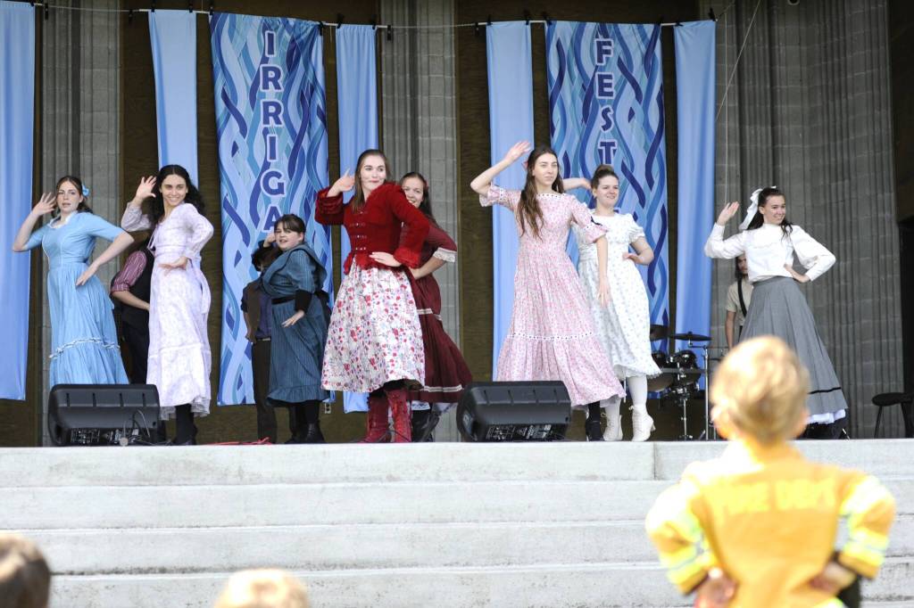 Sequim Gazette photo by Matthew Nash/ The Sequim High School operetta club performs a scene from Oklahoma! at the Family Fun Days on May 3 as 3-year-old Zephyr Lohman dances along in his firefighter costume.