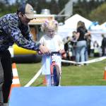 Kylan Johnson with Lincoln Park BMX helps 3-year-old Lutysa Palenga traverse a hill on a scooter bike on May 3 during the Sequim Irrigation Festivals Family Fun Days.
