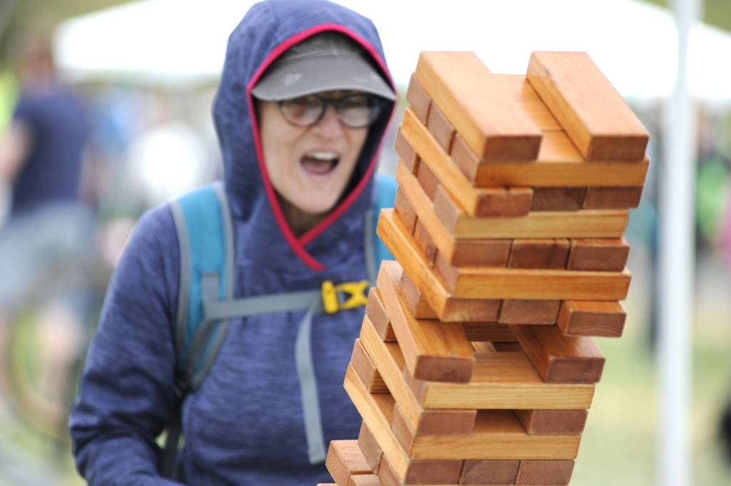 Sequim Gazette photo by Matthew Nash/ Melany Grogan of Sequim reacts to a move in a giant game of Jenga with her husband Nick and son Ernest at the Family Fun Days. The family participate in the Sequim Irrigation Festival every year, they said.