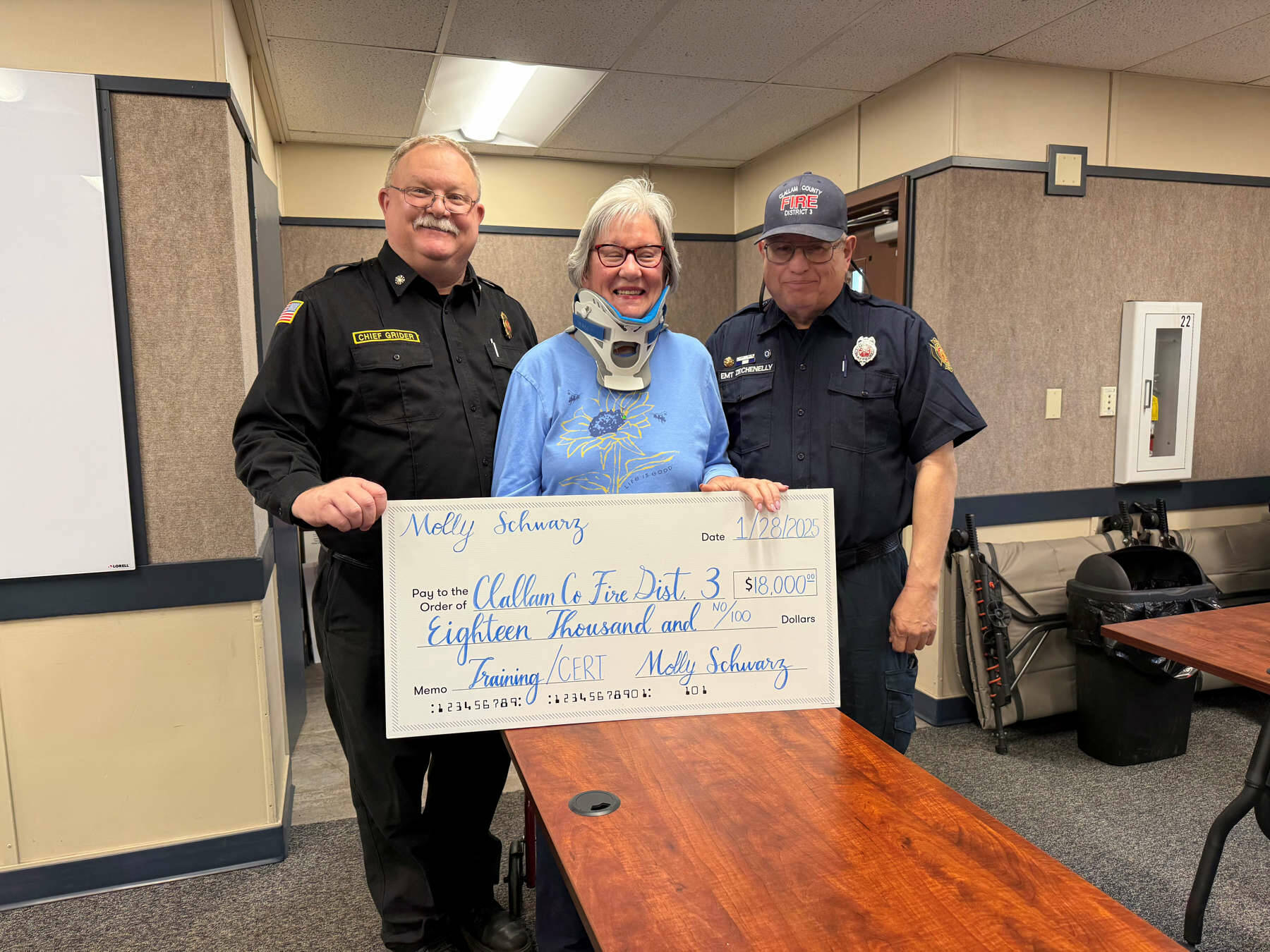 CCFD 3 Fire Chief Justin Grider, left, and Disaster Preparedness volunteer Blaine Zechenelly are all smiles during a ceremonial check presentation with donor Molly Schwarz of Sequim.