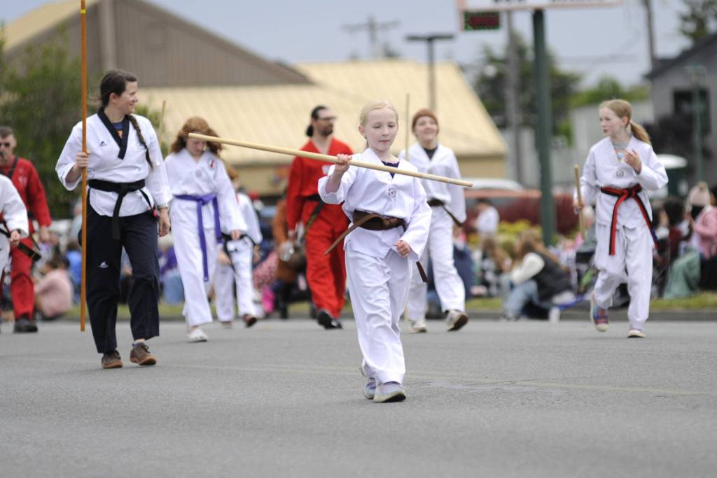 Sequim Gazette photo by Matthew Nash/ Skye Larsen, 8, of Port Angeles spins a bow staff with fellow members of White Crane Martial Arts during the Grand Parade.