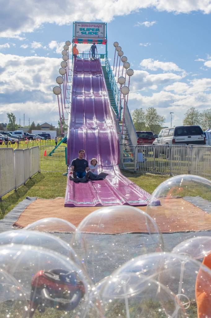 Sequim Gazette photo by Emily Matthiessen/ The European Super Slide was a hit with young and old at the Logging Show last weekend. Piper Jorngsen, almost 6, holds tight to her father Riley as they reach the bottom.