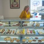 Sequim Gazette photo by Emily Matthiessen/ Laura Shaw prepares a cupcake from the case at Donuts, Cakes and More Bakery.