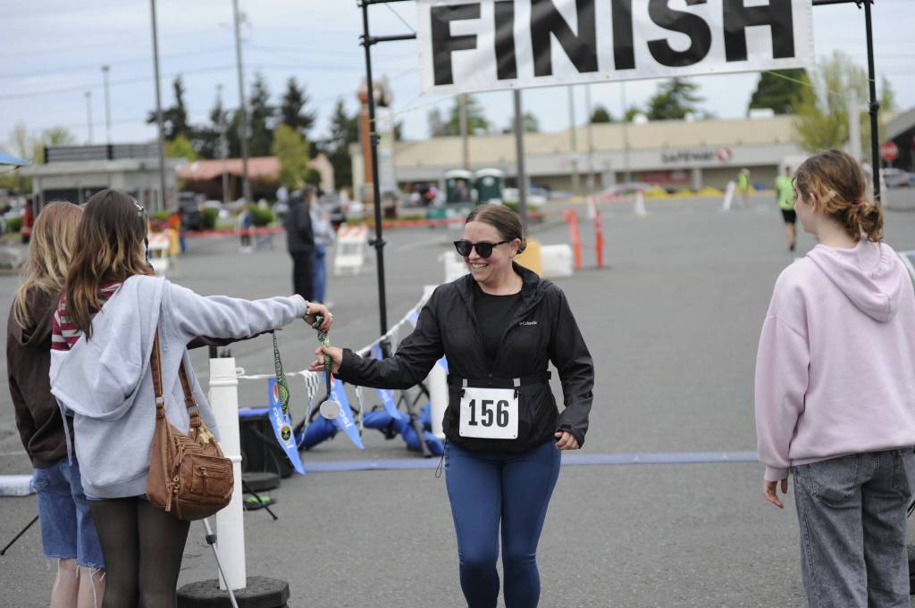 Sequim Gazette photo by Matthew Nash/ Carolyn Hamilton of Sequim receives a medal after finishing the one mile race of the Irrigation Festivals Run Series.