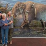 Sequim Gazette photo by Emily Matthiessen
From left, Clare Manis Hatler of Sequim, Charlene Gustafson and Vera Morgan paid a visit to the Sequim Museum and Arts at 544 N. Sequim Ave. last week. The trio have been friends for nearly 50 years after seven summers spent investigating the mastodon bones discovered on Manis Hatlers property by her late husband Manny Emanuel Manis. Gustafsons late husband, Carl Eugene Gus Gustafson, an associate professor at Washington State University, led research teams of graduate students at the Manis property in Happy Valley. One of those graduate students was Morgan, who is now retired and living in New Mexico after a career as an archeologist, including excavating a site for the U.S. Highway 101 bypass in Sequim. The women stand before the museums life-sized mural with some of the mastodons nearly 14,000-year-old bones.