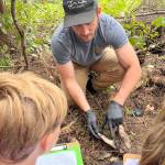 Photo courtesy of Five Acre School/
At a cougar kill site on the outskirts of Sequim, Andy Stratton, project coordinator for the Olympic Cougar Project, shows Five Acre second-third grade students the skull of the cougars prey, a young deer.
