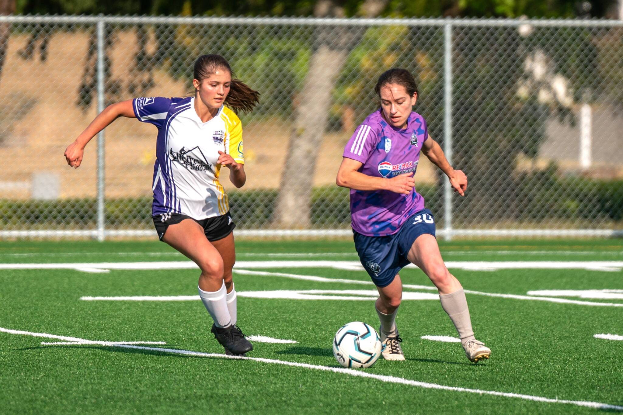 Photo by Devin Beck/ Sabrina Wilk with the NPFC Blaze moves past Raimey Brewer with the Sequim Junior Soccer U19 Queens on June 14 in Port Angeles. The Blaze won 6-0 as part of their Appreciate Night event on June 14.