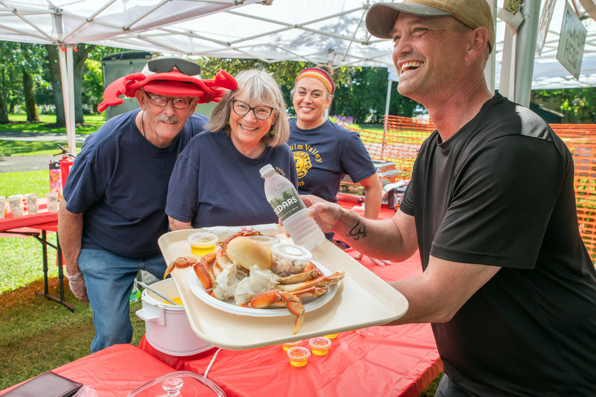 Sequim Gazette photo by Emily Matthiessen / At Sequim Valley Lions 12th annual Crab Feed in Pioneer Park on Saturday Eric MacDonald holds a plate with a whole crab dinner. MacDonald said that this was the first time hed attended. From left to right in the background, Stan Dame, Josie Carroll and Vanessa Mills served food with a smile at the five hour event which also featured live music from Dawn and Steve and a silent auction.