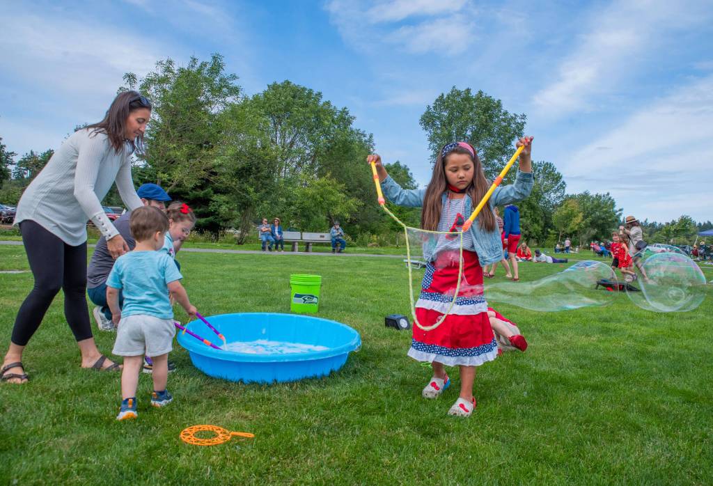 Sequim Gazette photo by Emily Matthiessen/ Laura Dyer and children Leon, 2, and Olivia, 4, and Madison Casteel, 7, play with bubbles supplied by the City of Sequim during Fridays Independence Day celebration at Carrie Blake Community Park.