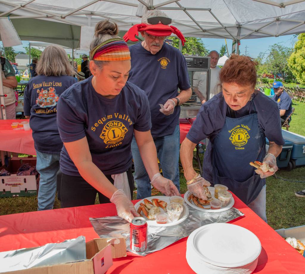 Sequim Gazette photo by Emily Matthiessen/ Sequim Valley Lions Club members Vanessa Mills, Stan Dame and June Nicholas prepare plates of Dungeness Crab at the 12th Annual Crab Feed in Pioneer Memorial Park June 28. 450 crabs were bought and sold for the event, which raised money for local projects and other non-profits.