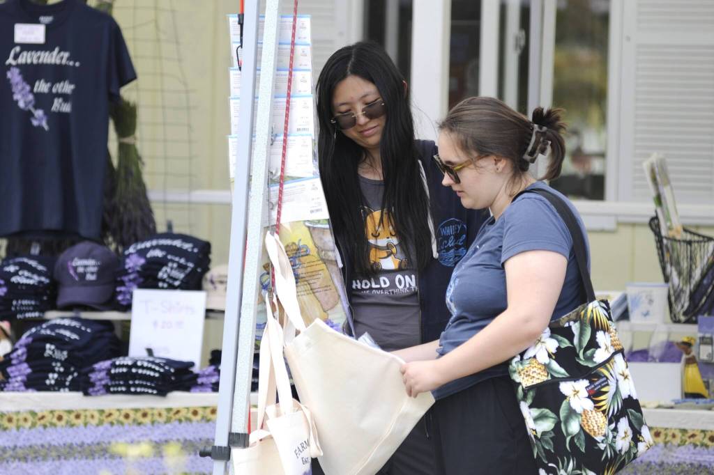 Sequim Gazette photo by Matthew Nash/ Alice Xing of Redmond and Miranda Draper of Shoreline look wares at Nelsons Duckpond and Lavender Farm during the Sequim Lavender Festival.
