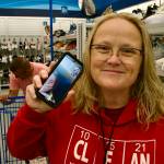 Sequim Gazette photo by Jacques Star/ Tammy Blessing holds up her cell phone, through which she is communicating with her daughter, Taylor White. She and her husband Cassidy Blessing (behind her) shop for a new pair of school shoes for Taylor with a gift card provided by H.U.M.A.N., a new Sequim nonprofit created by Cassidys former bosses, Darrin and Alicia Liggins.