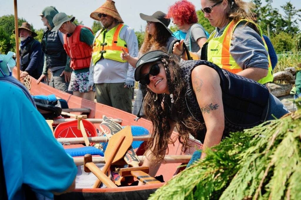 Sequim Gazette photo by Jacques Star/ Dezi Rose of the Jamestown SKlallam Tribe secures a canoe on the beach and discusses the journey with her fellow tribal members.